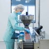 Pharmaceutical technician in sterile environment working on production of pills at pharmacy factory