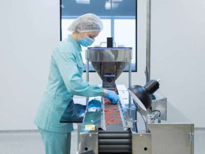 Pharmaceutical technician in sterile environment working on production of pills at pharmacy factory