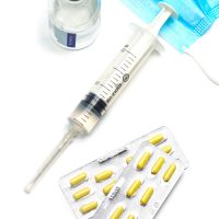 Syringe, capsules,and  medical mask bottle on white background